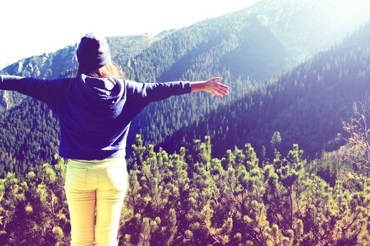 Happy teenage girl feel freedom in mountains scenery. Vintage instagram picture.