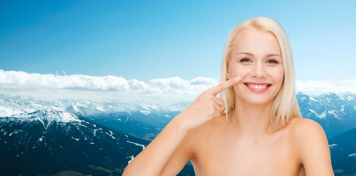 health and beauty concept - smiling young woman pointing to her nose