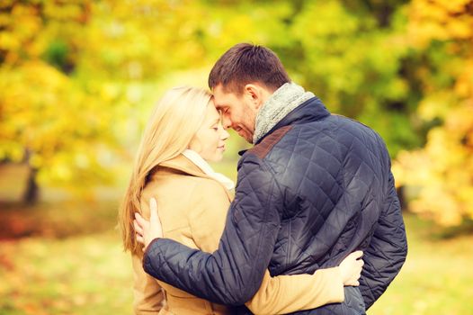 holidays, love, travel, relationship and dating concept - romantic couple kissing in the autumn park