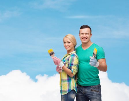 repair, construction and maintenance concept - smiling couple with paintbrush