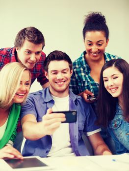 education concept - group of students looking into smartphone at school