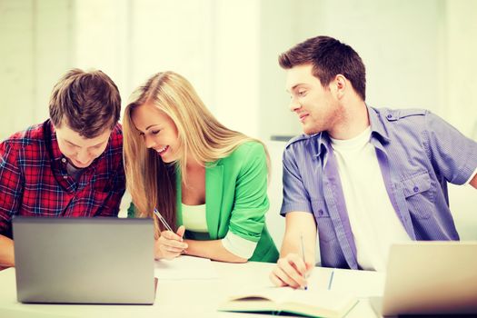 education concept - students writing something in notebooks at school