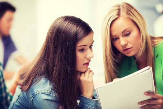 education concept - student girls looking at notebook at school