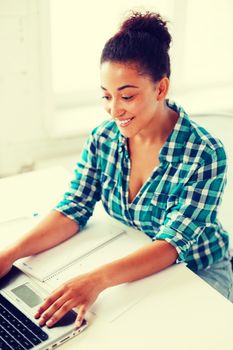 education concept - smiling international student girl with laptop at school