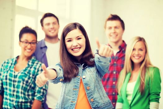 education concept - happy team of students showing thumbs up at school