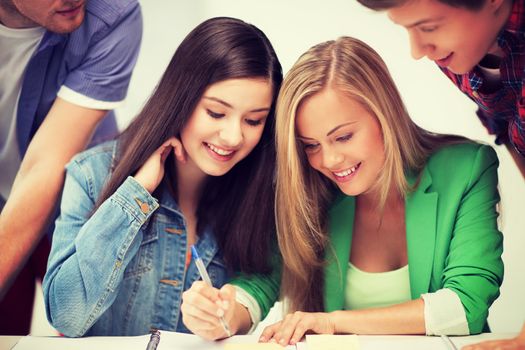 education concept - students pointing at notebook at school