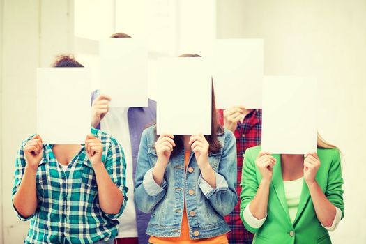 education concept - group of students covering faces with blank papers