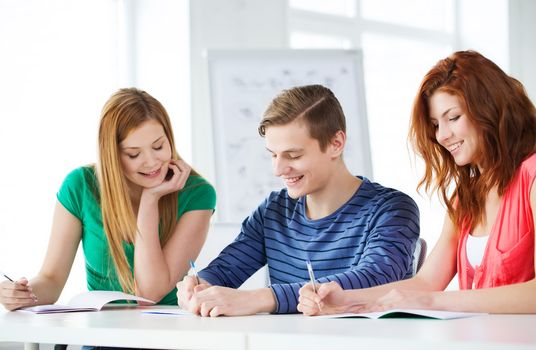 education and school concept - three smiling students with textbooks at school