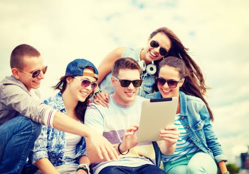 summer holidays, teenage and technology concept - group of smiling teenagers in eyeglasses looking at tablet pc outdoors