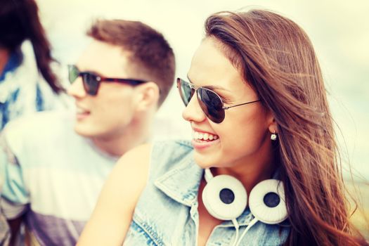 summer holidays, people and happiness concept - smiling teenage girl in sunglasses outdoors with friends