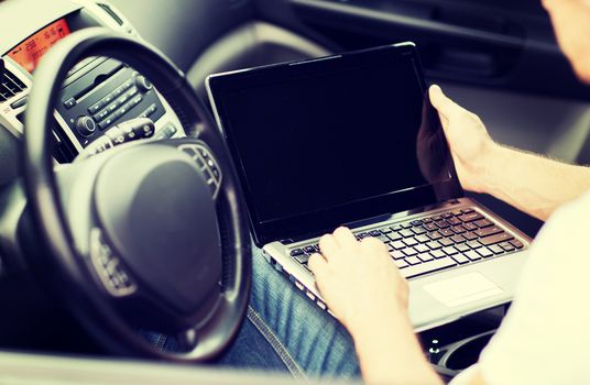 transportation and vehicle concept - man using laptop computer in car