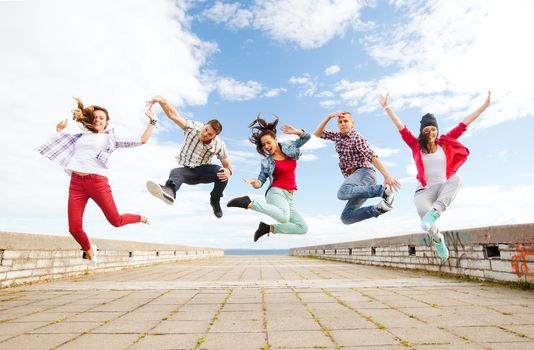summer, sport, dancing and teenage lifestyle concept - group of teenagers jumping