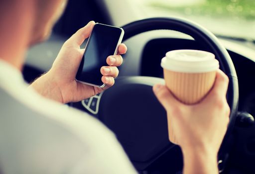 transportation and vehicle concept - man drinking coffee and using phone while driving the car