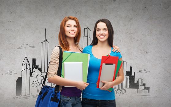 education, technology and people concept - two smiling students with bag, folders and tablet pc standing