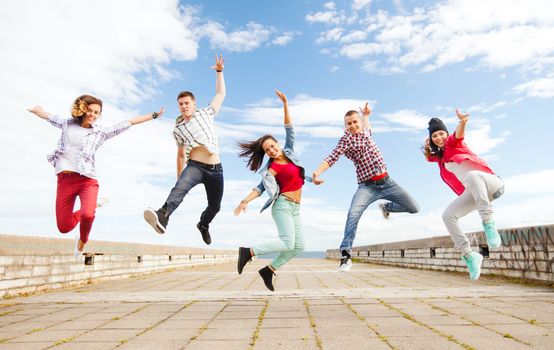 summer, sport, dancing and teenage lifestyle concept - group of teenagers jumping