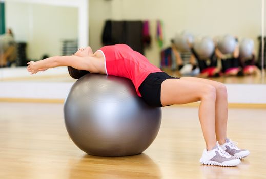 fitness, sport, training, gym and lifestyle concept - young woman doing exercise on fitness ball