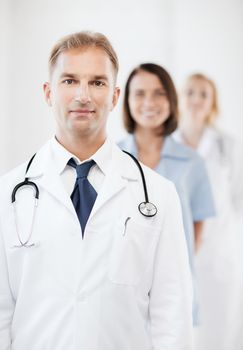 healthcare and medical concept - male doctor with stethoscope and colleagues