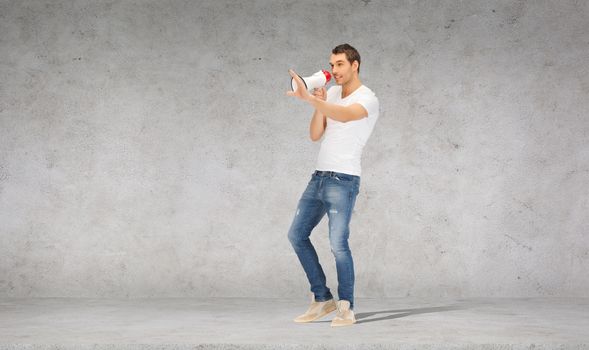 communication concept - handsome man with megaphone over concrete wall