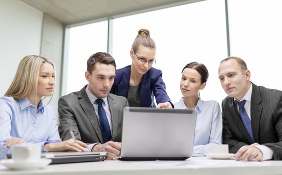 business, technology and office concept - serious business team with laptop computers, documents and coffee having discussion in office