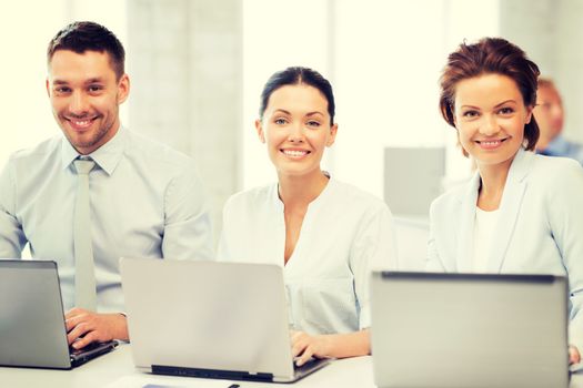 picture of group of people working with laptops in office