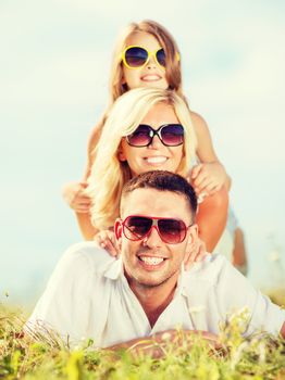 summer holidays, children and people concept - happy family with blue sky and green grass