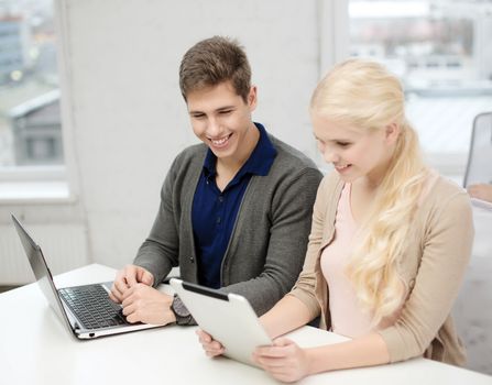 school, education, technology and internet concept - two teens with laptop and tablet pc at school