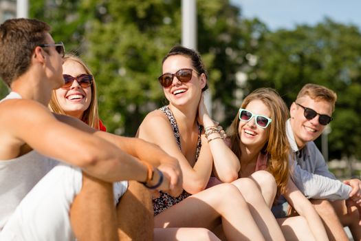 friendship, leisure, summer and people concept - group of smiling friends sitting on city street