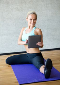 fitness, technology and sport concept - smiling woman with tablet pc sitting on in gym