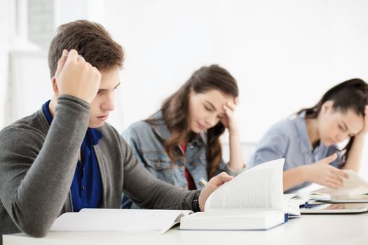 school and education concept - group of tired students with notebooks at school