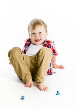 Funny blue-eyed three-year boy on a light background. Studio photo