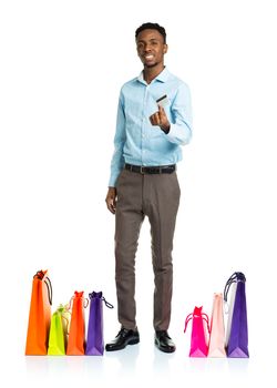 Happy african american man with shopping bags and holding credit card on white background. Shopping and holidays concept