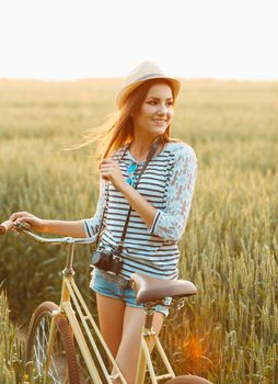 Lovely young woman stands in a field with her bicycle. Lifestyle concept