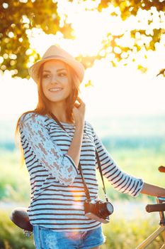 Lovely young woman in a hat riding a bicycle in a park. Active people. Outdoors