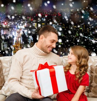 family, christmas, holidays and people concept -smiling father and daughter with gift box over snowy night city background