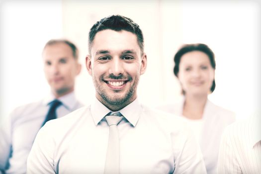 business concept - smiling handsome businessman with team in office