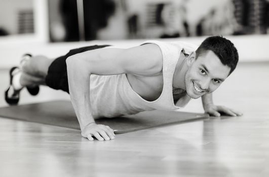 fitness, sport, training, gym and lifestyle concept - smiling man doing push-ups in the gym