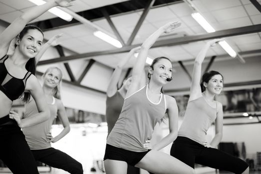 fitness, sport, training, gym and lifestyle concept - group of smiling people stretching in the gym