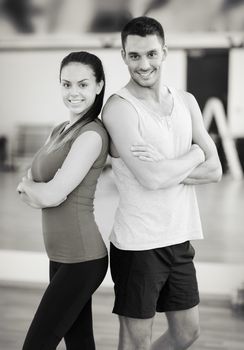 fitness, sport, training, gym and lifestyle concept - two smiling people in the gym