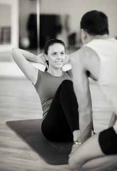 fitness, sport, training, gym and lifestyle concept - male trainer with woman doing sit ups