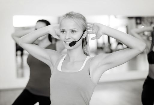 fitness, sport, training, gym and lifestyle concept - group of smiling people with trainer exercising in the gym