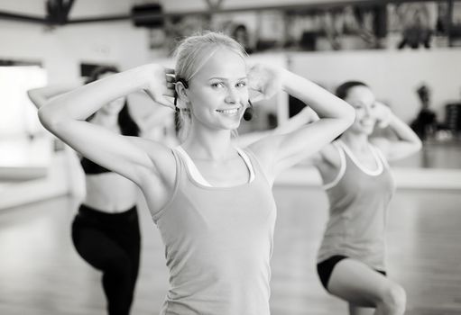 fitness, sport, training, gym and lifestyle concept - group of smiling people with trainer exercising in the gym