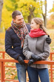 love, relationship, family, season and people concept - smiling couple hugging on bridge in autumn park