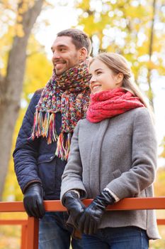 love, relationship, family, season and people concept - smiling couple hugging on bridge in autumn park