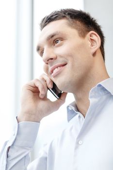 business, technology and office concept - smiling businessman with smartphone in office