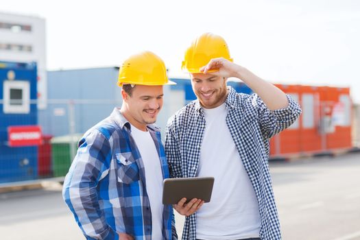 business, building, teamwork, technology and people concept - group of smiling builders in hardhats with tablet pc computer outdoors