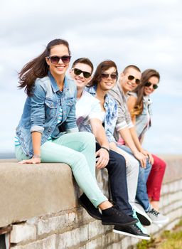 summer holidays and teenage concept - group of teenagers hanging out outside