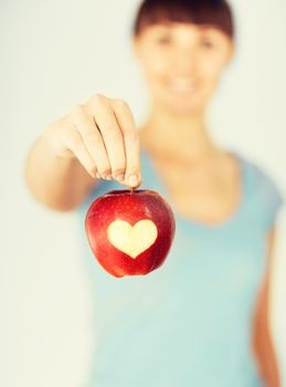 healthy food and lifestyle - woman hand holding red apple with heart shape