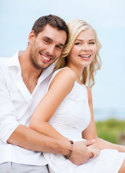 summer holidays and dating concept - couple in shades sitting at sea side