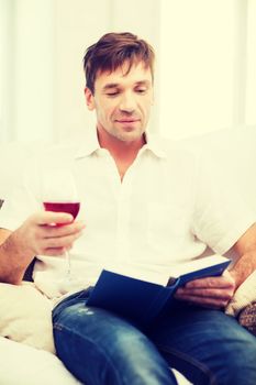 leisure, drinks, retirement, education and lifestyle concept - happy man with book and glass of rose wine at home