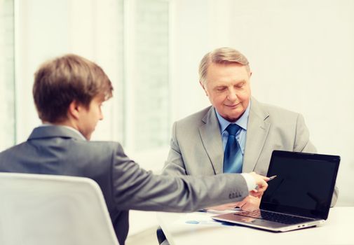 business, advertisement, technology and office concept - older man and young man with laptop computer in office